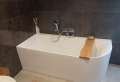 Badkamer met ligbad en grijs tinten